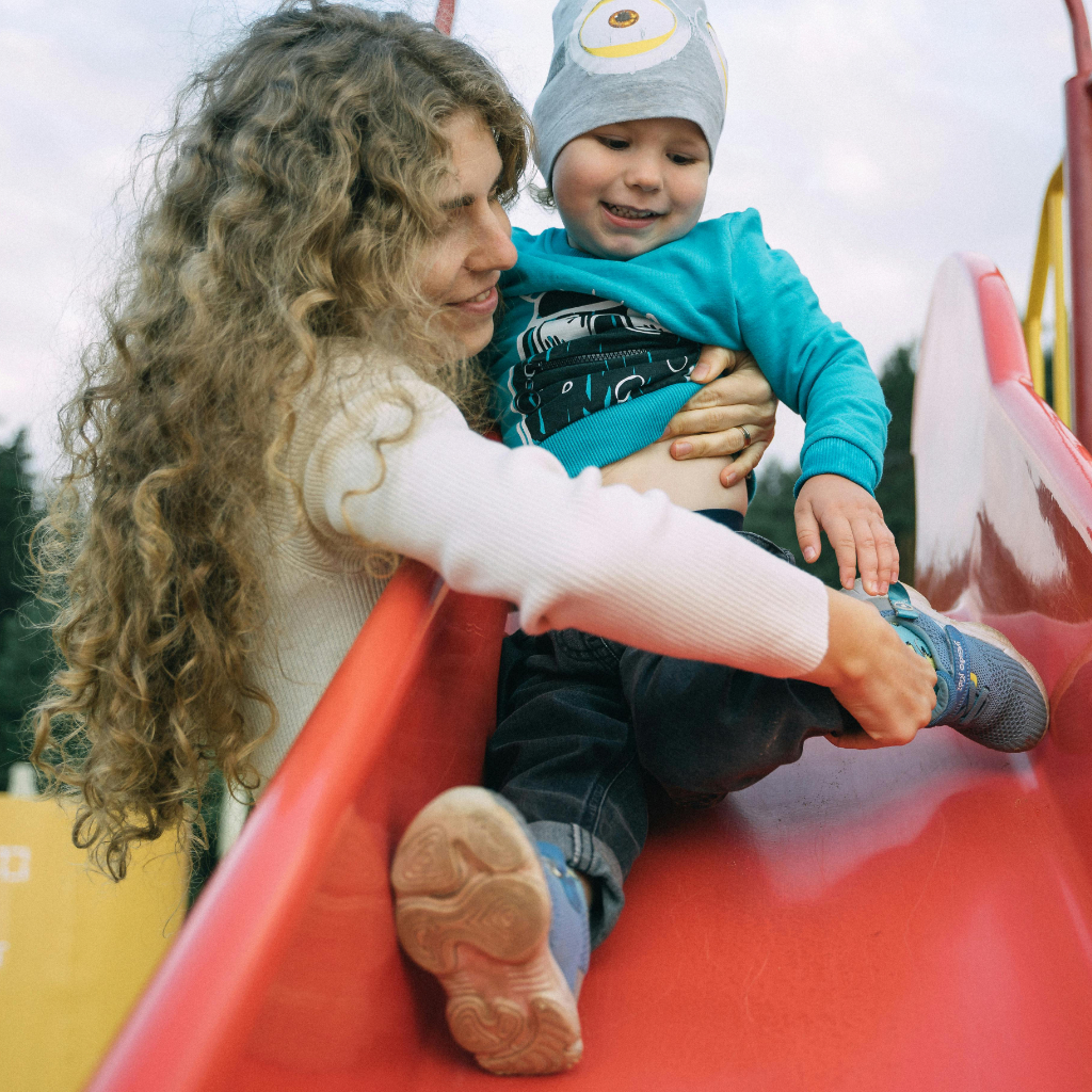 A mother helping her child onto a slide